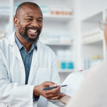 Pharmacy, medicine and pharmacist in discussion with a patient explaining her prescription. Healthcare, medical and African male chemist speaking to a woman at a pharmaceutical clinic or drug store.